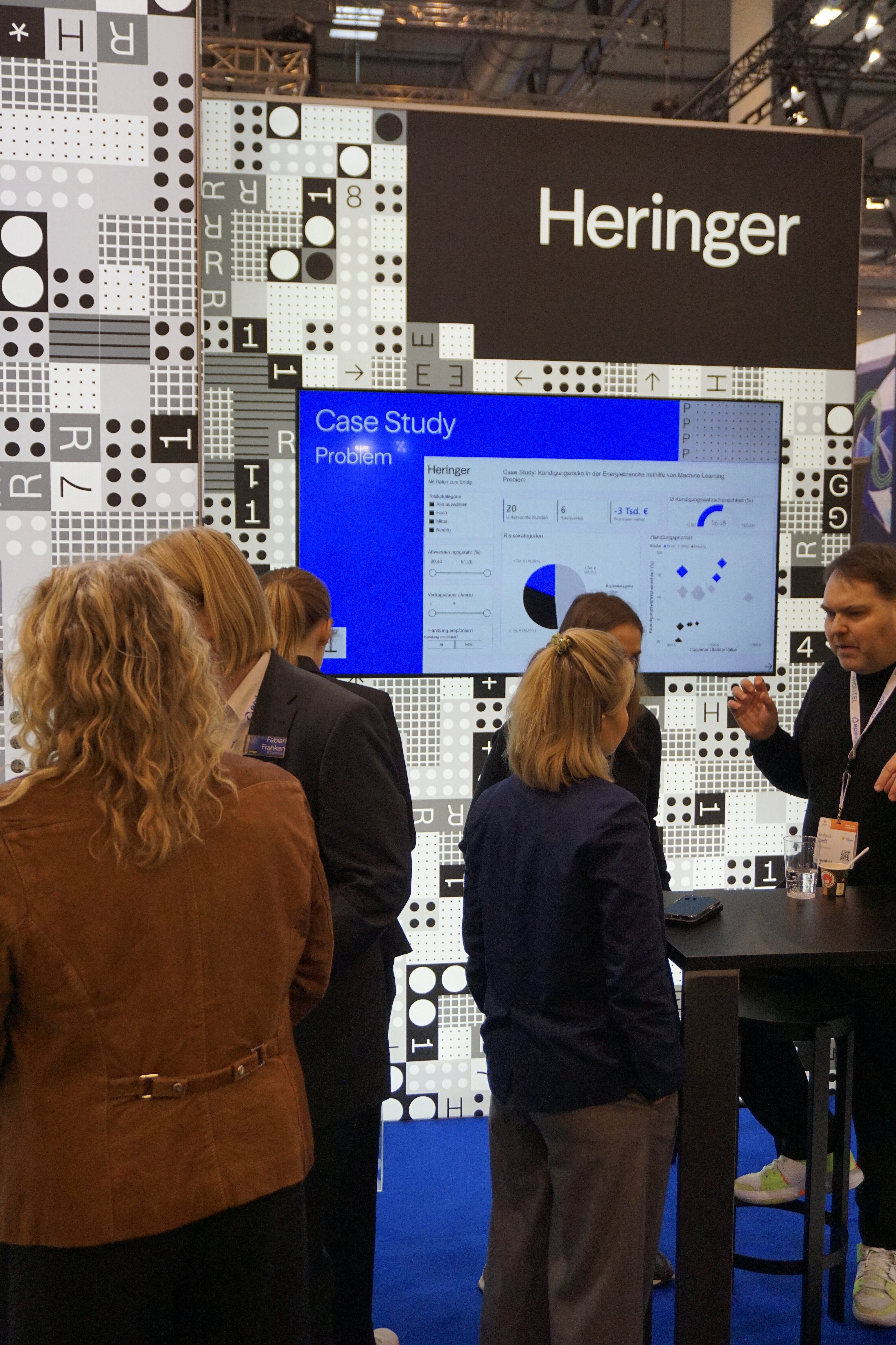 Mehrere Personen stehen am Stand der Heringer Consulting GmbH und sprechen miteinander